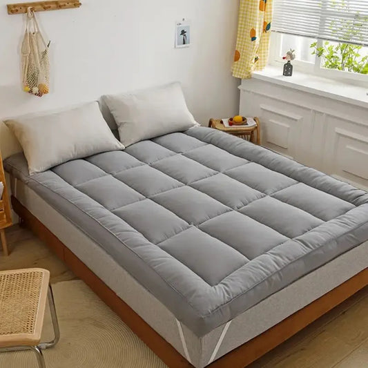Gray quilted king mattress topper pad on a bed