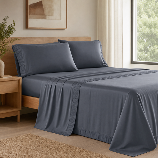 Dark grey cooling queen sheet set on a made bed in a bright bedroom