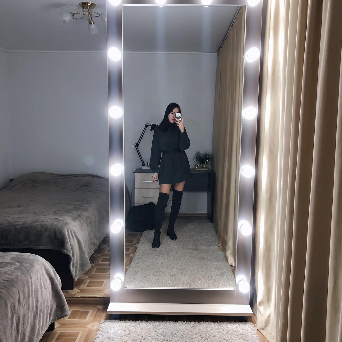 Mirror photo of the dark oversized turtleneck sweater dress worn with boots